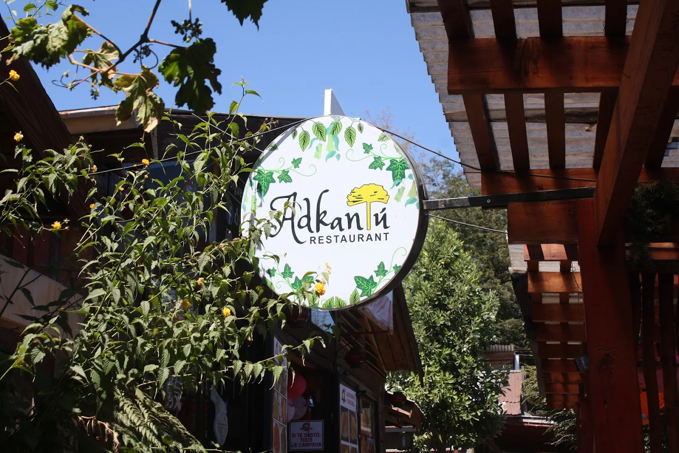 Cartel de Adkantú colgado entre las plantas de la terraza.