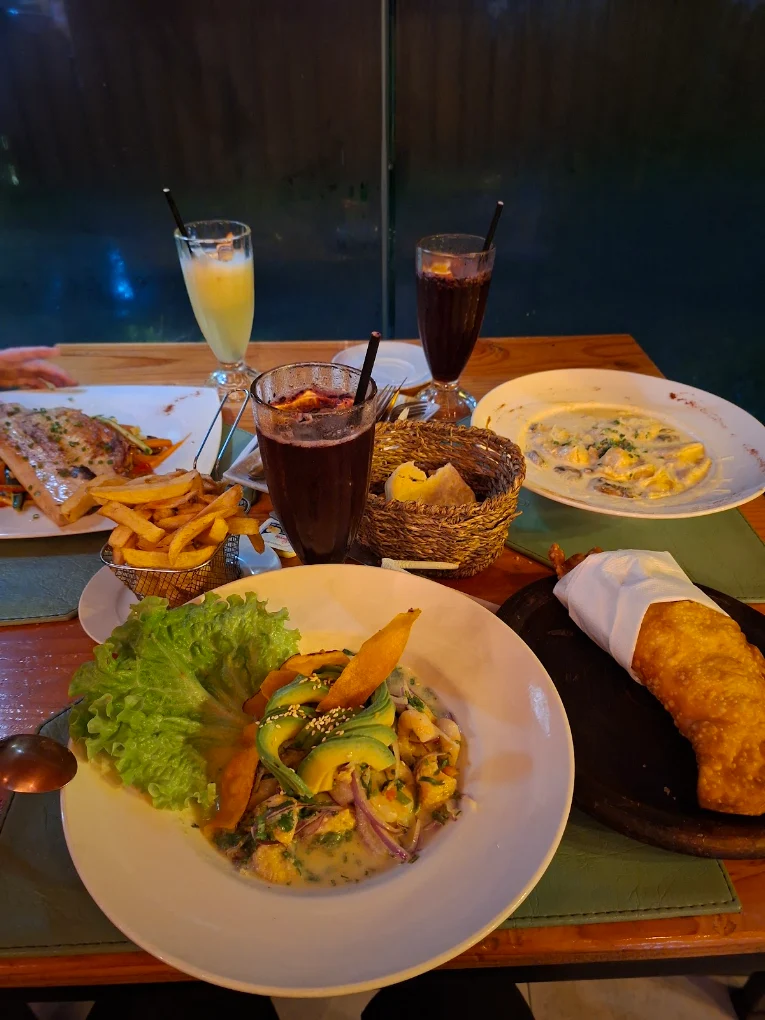 Mesa servida de noche, con varios platos y tragos entre amigos.