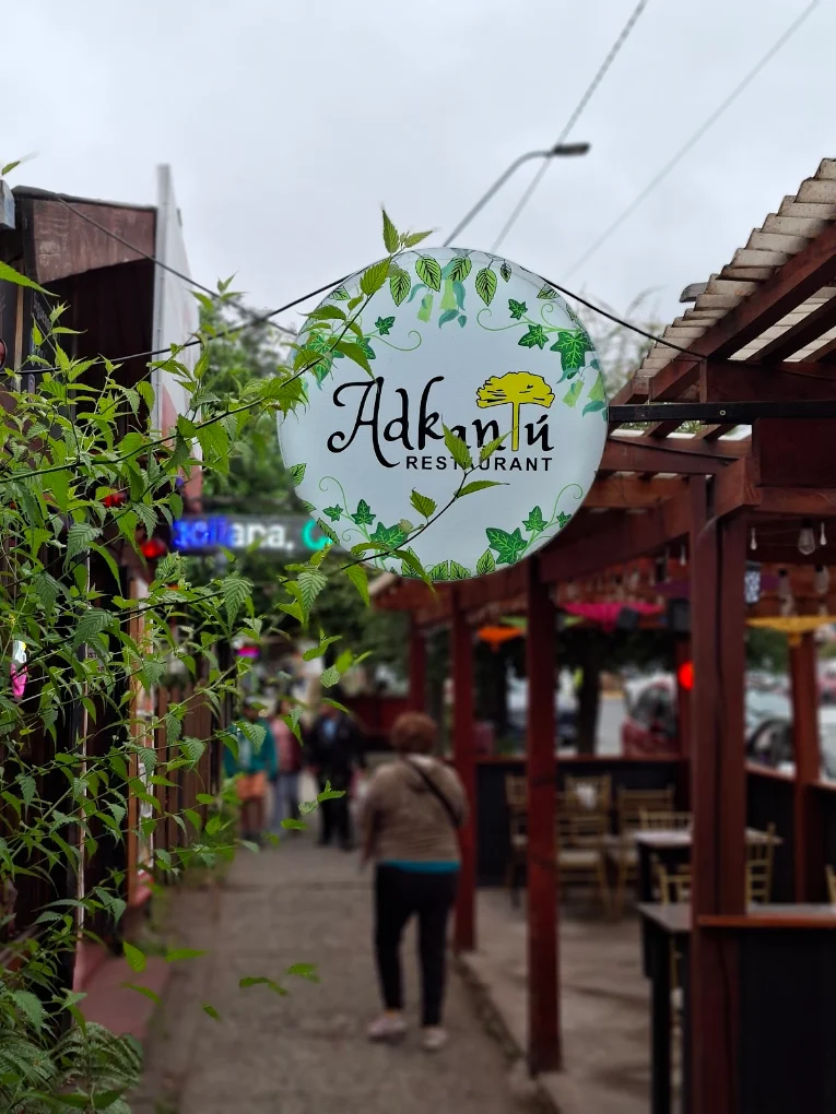 Pasaje de entrada con el logo de Adkantú colgado y gente caminando hacia el comedor.