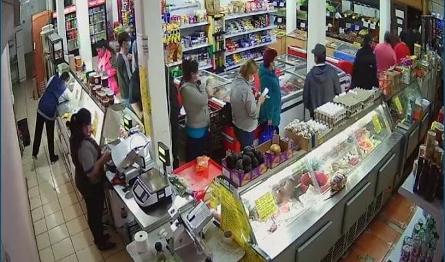 Mesón de atención del local, con la vitrina de fiambres y clientes esperando su turno.
