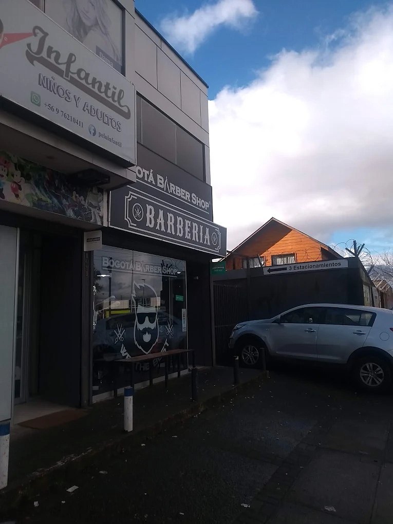Fachada del segundo local de Bogotá Barber Shop de día, con el letrero de barbería y estacionamiento al lado