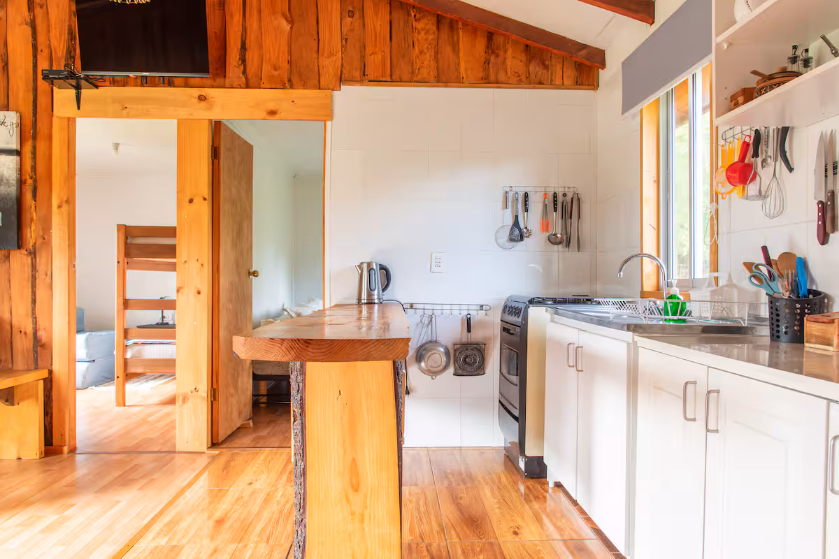 Cocina equipada con mesón de madera, refrigerador y cocina a gas