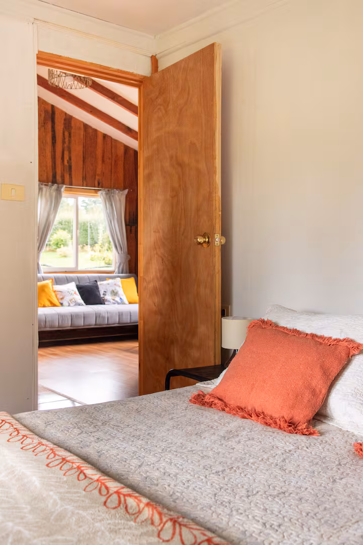 Dormitorio visto desde la puerta, con cama de plaza y media y cojines