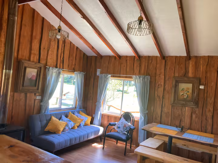 Living con sofá azul y sillón junto al ventanal