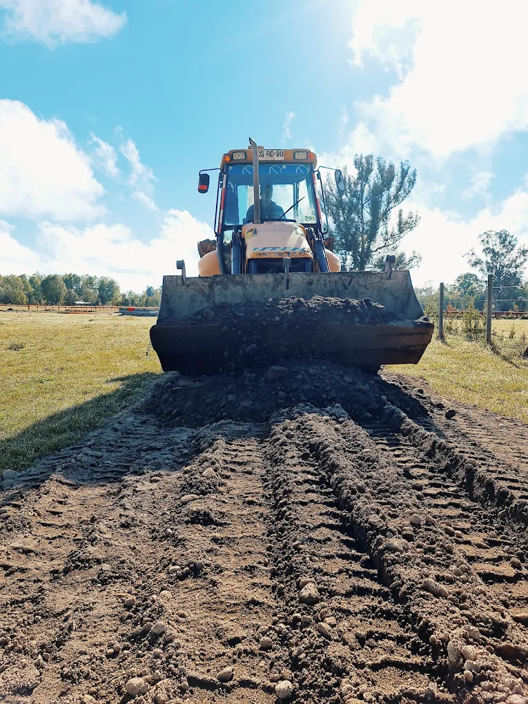 Bulldozer de oruga emparejando y escarificando un terreno, con el cielo despejado al fondo.