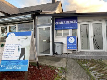 Entrada de la clínica desde la vereda, con el letrero «Clínica Dental» y un pendón con los servicios.