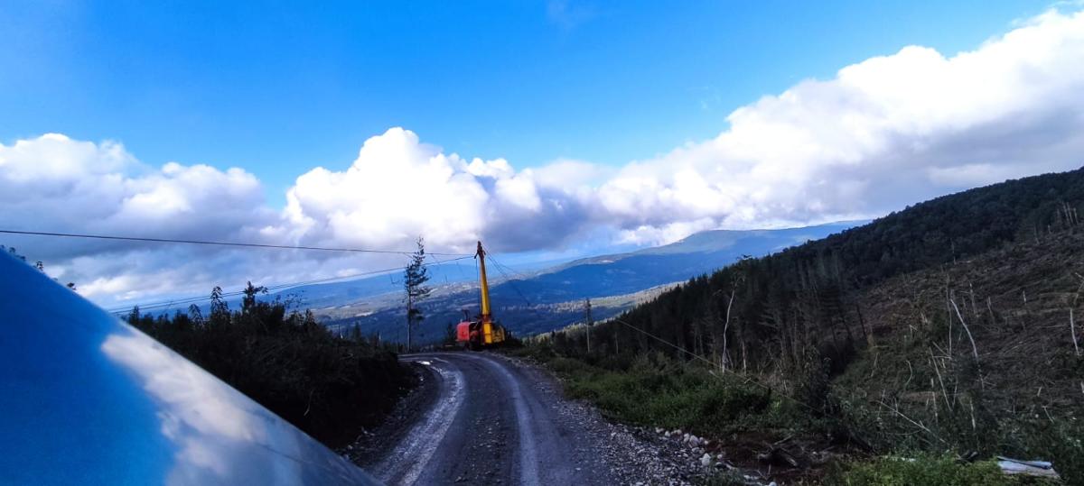 Torre de madereo instalada junto al camino forestal, con las líneas tendidas hacia el valle
