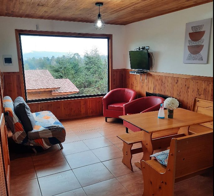 Living de la Cabaña 1 con ventanal al bosque