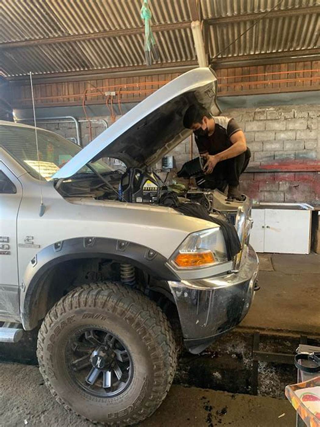Camioneta con el capó abierto y un mecánico trabajando en el motor.