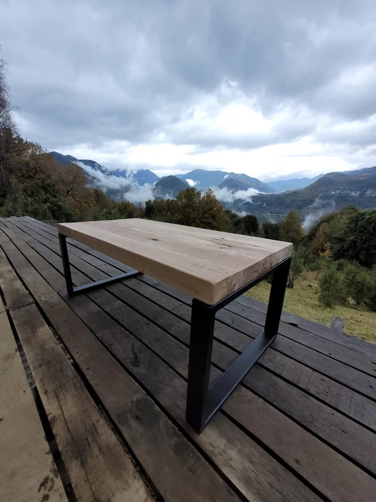 Mesa de exterior con estructura de fierro y cubierta de madera, sobre un deck.