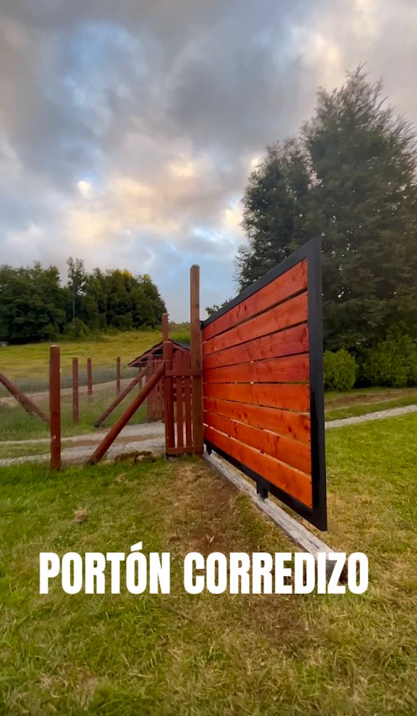 El mismo tipo de portón corredizo visto en diagonal, con el poste guía de madera a la izquierda.