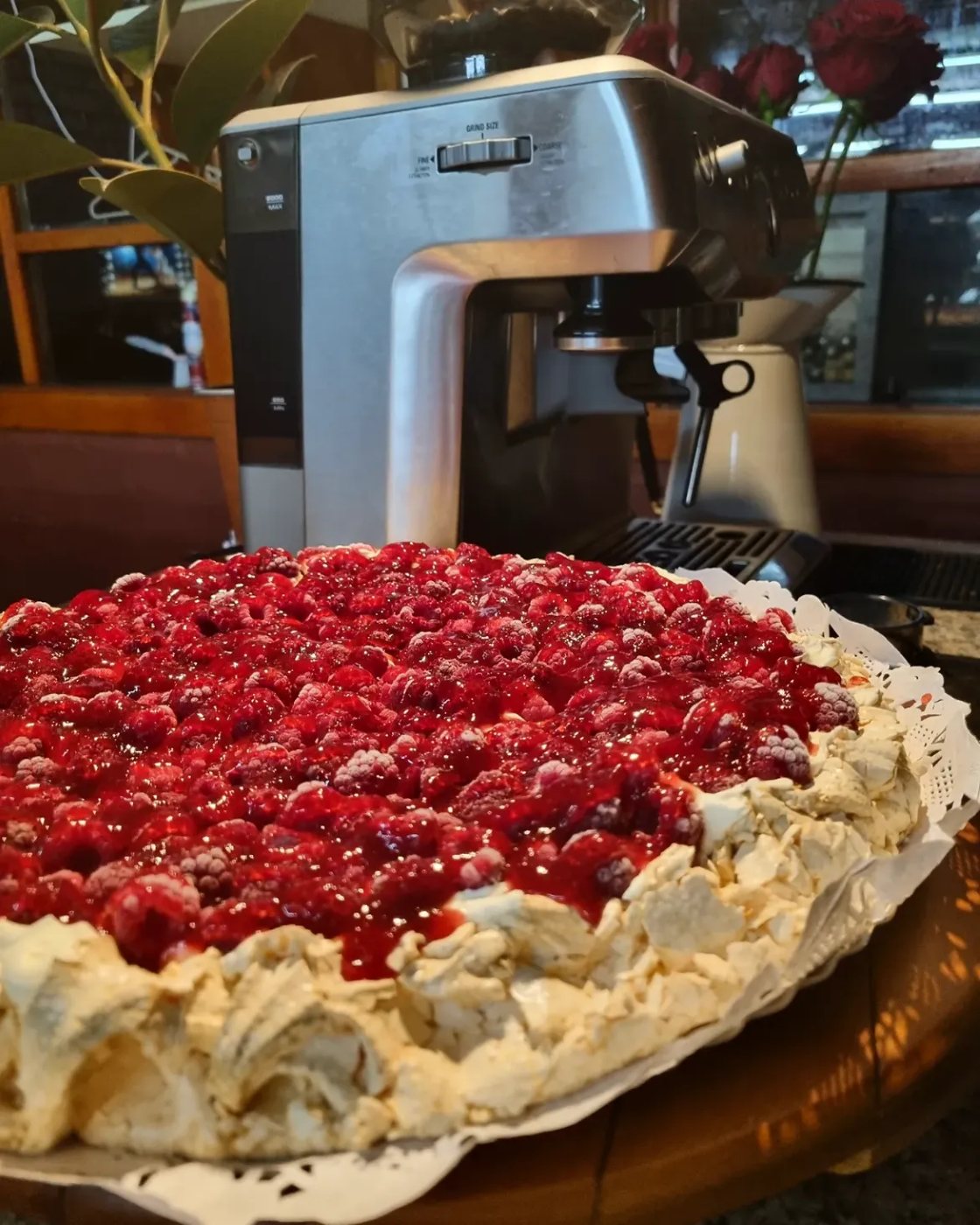 Pavlova de frambuesa entera sobre el mesón de la cafetería